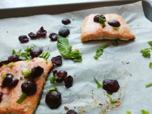finished whole 30 baked salmon on sheet pan with cherries and fresh mint