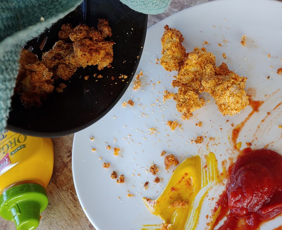 whole30 air fryer chicken nuggets tossed onto plate from the air fryer basket