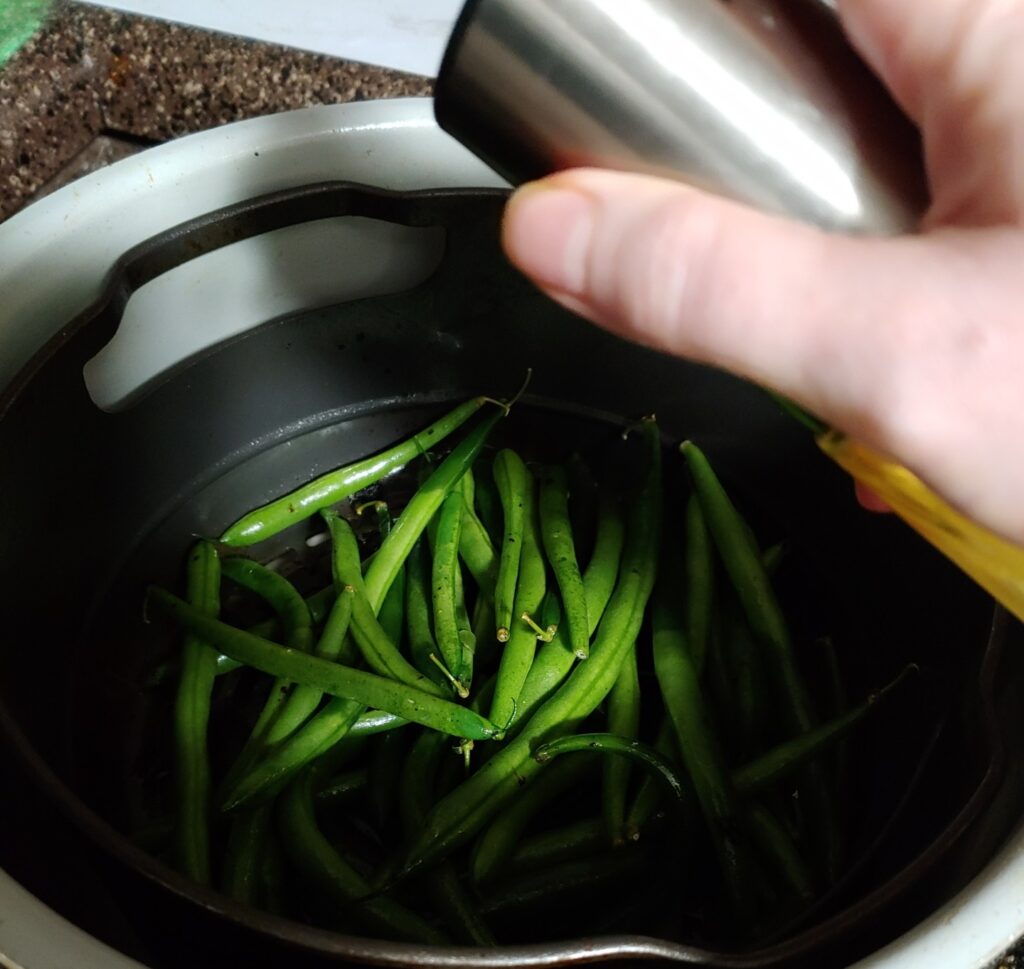 spraying green beans with extra oil