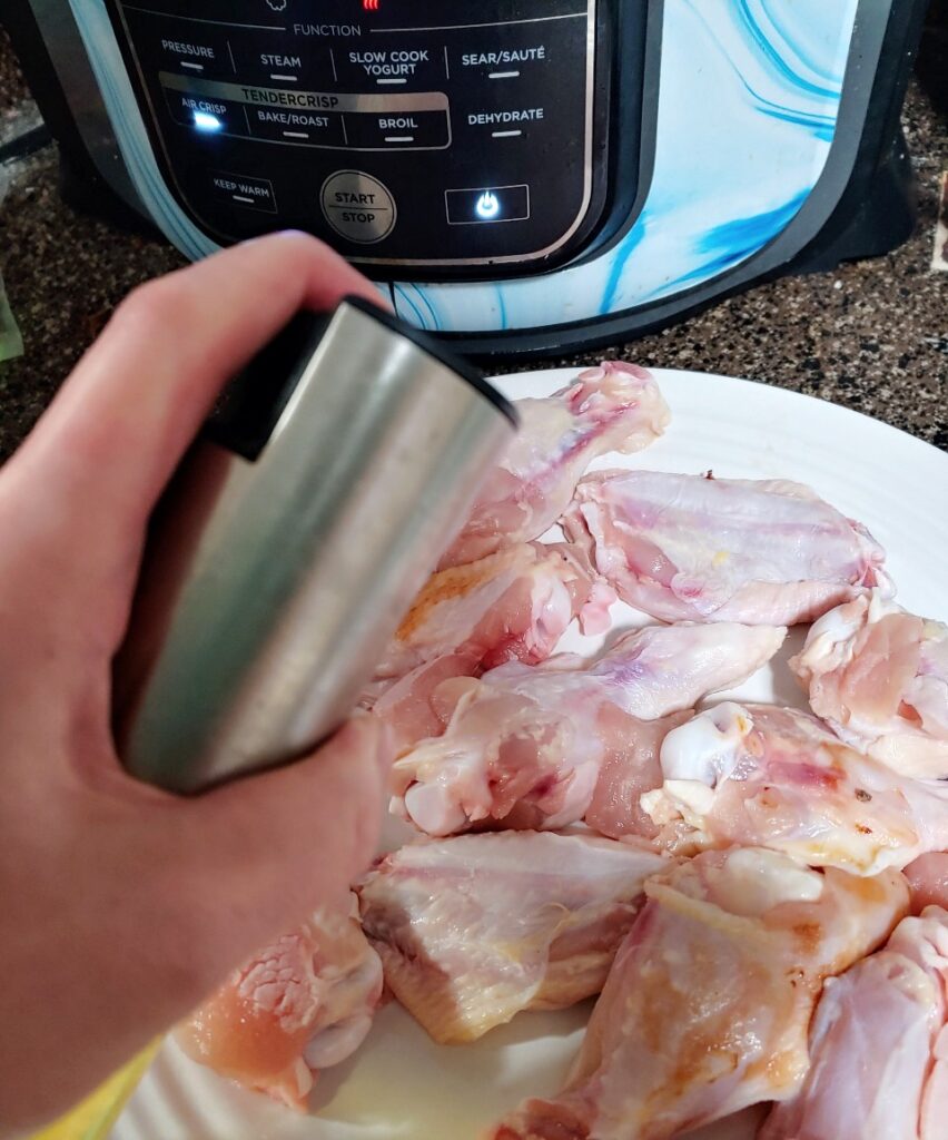 chicken wings being sprayed with oil