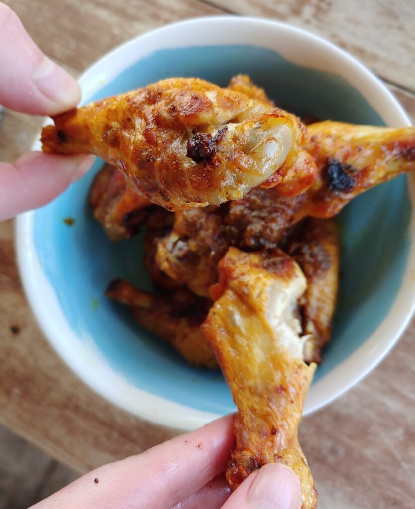 air fryer curry chicken wings being grabbed from bowl